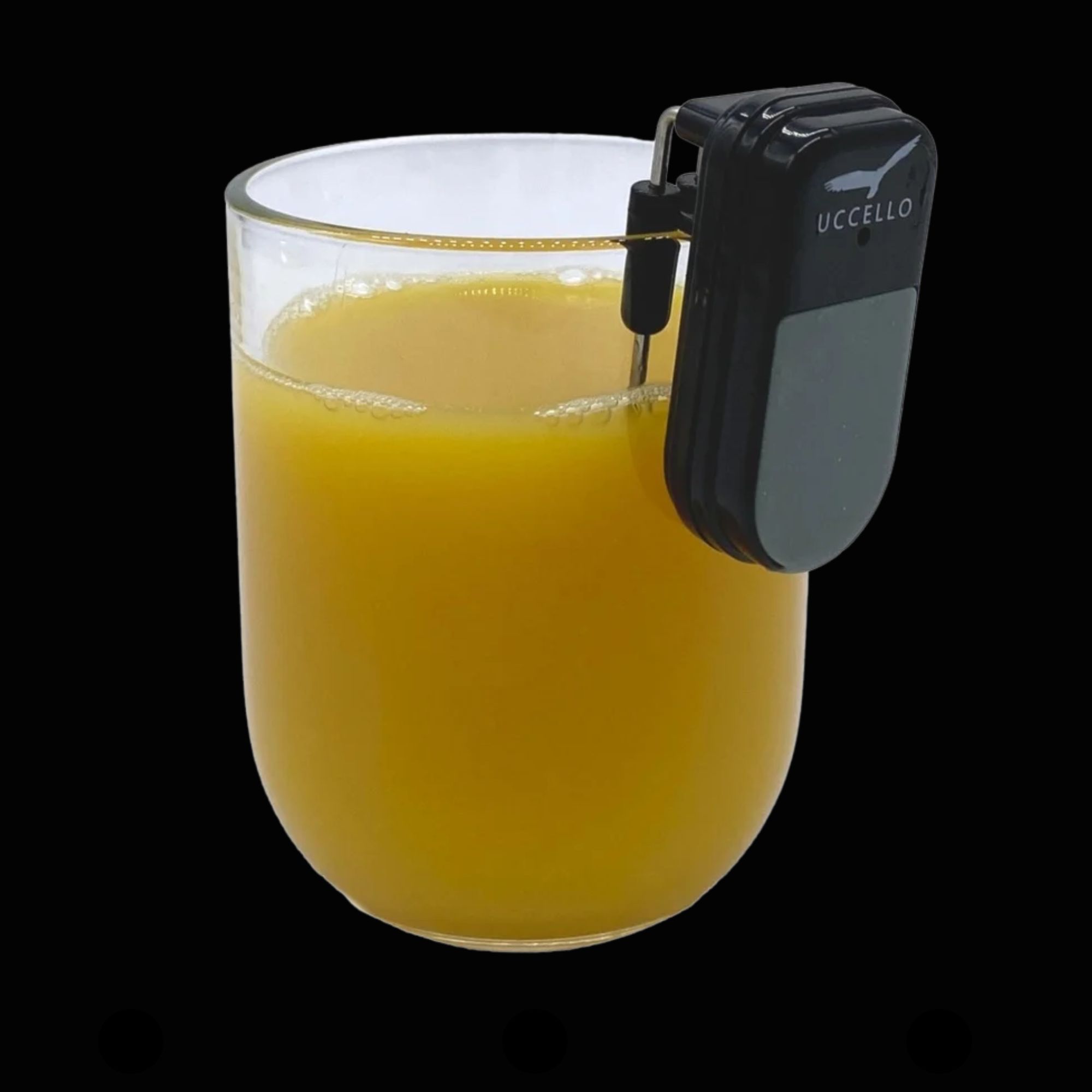 Ein Glassensor ist am Rand eines Glases mit Orangensaft befestigt. Das kleine Gerät erkennt den Füllstand und gibt beim Einschenken ein akustisches Signal, sobald das Glas voll ist.